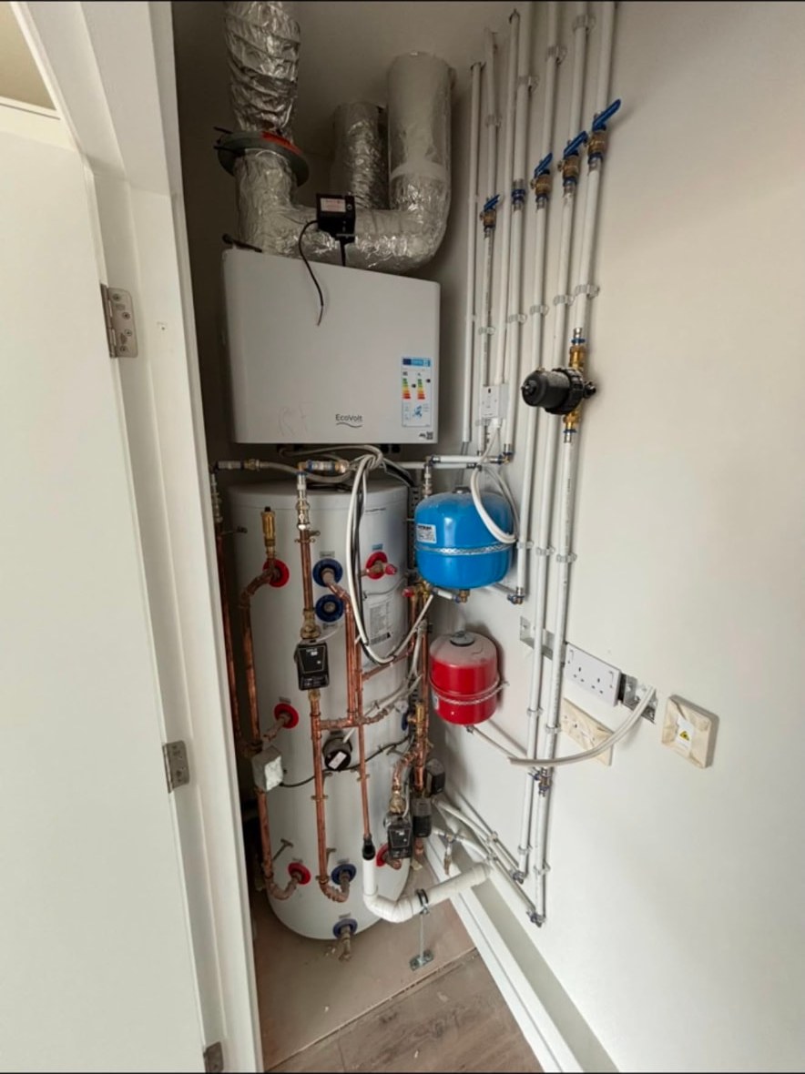Utility cupboard with a hot water cylinder, copper pipework, expansion vessels and valved distribution pipework