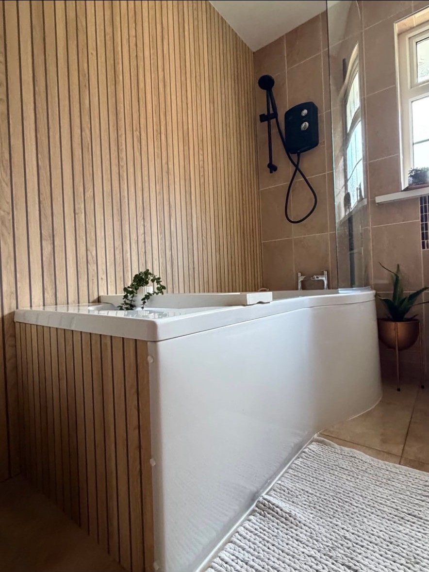 Bathroom with a panelled bath surround and wall mounted electric shower