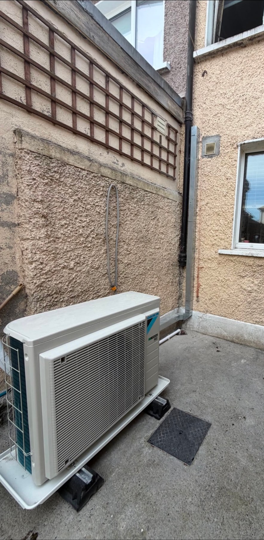 Wall mounted air conditioning outdoor condenser unit with trunked refrigerant pipework
