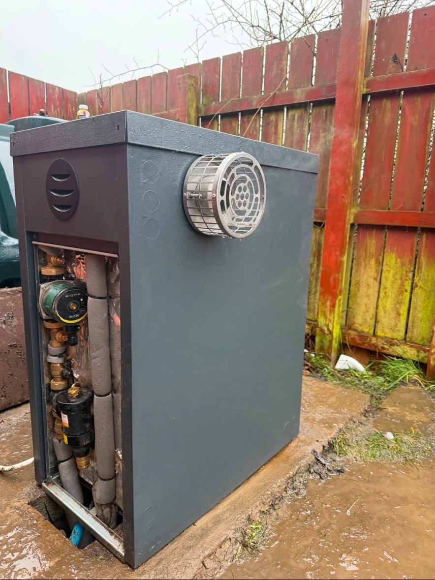 External oil boiler housing with pump, magnetic filter and insulated pipework inside the casing