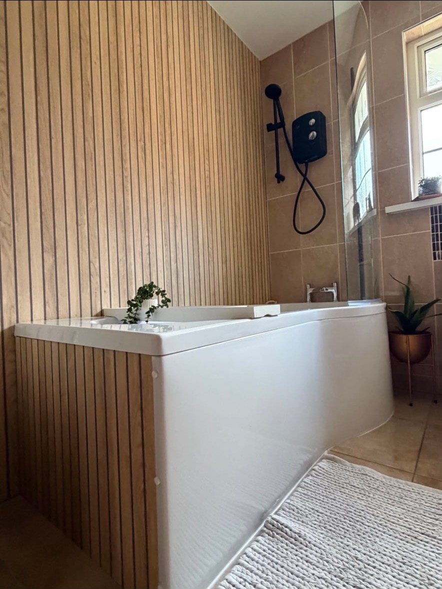 Completed bathroom installation with panelled bath and electric shower