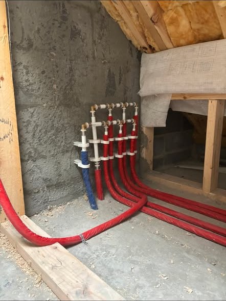 Plumbing manifold with insulated hot and cold pipework runs in an attic space