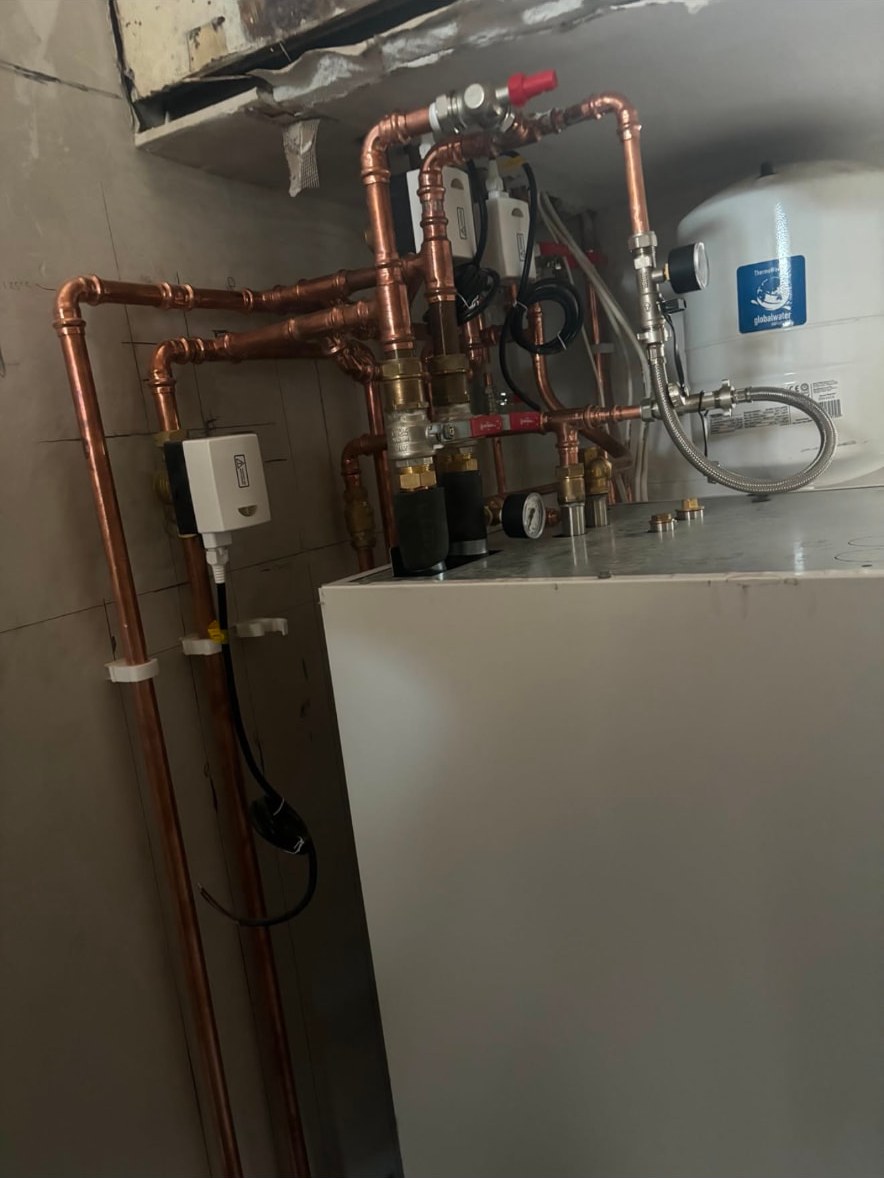 Copper pipework, zone valves, pressure gauge and expansion vessel above a hot water cylinder