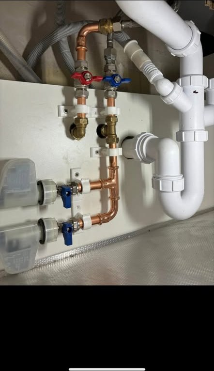 Copper pipework with hot and cold isolation valves and waste connections under a sink